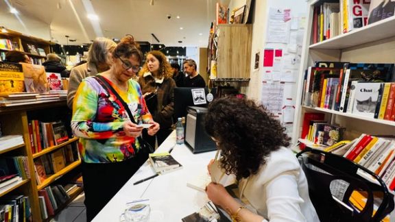a woman is signing a book in a bookstore .