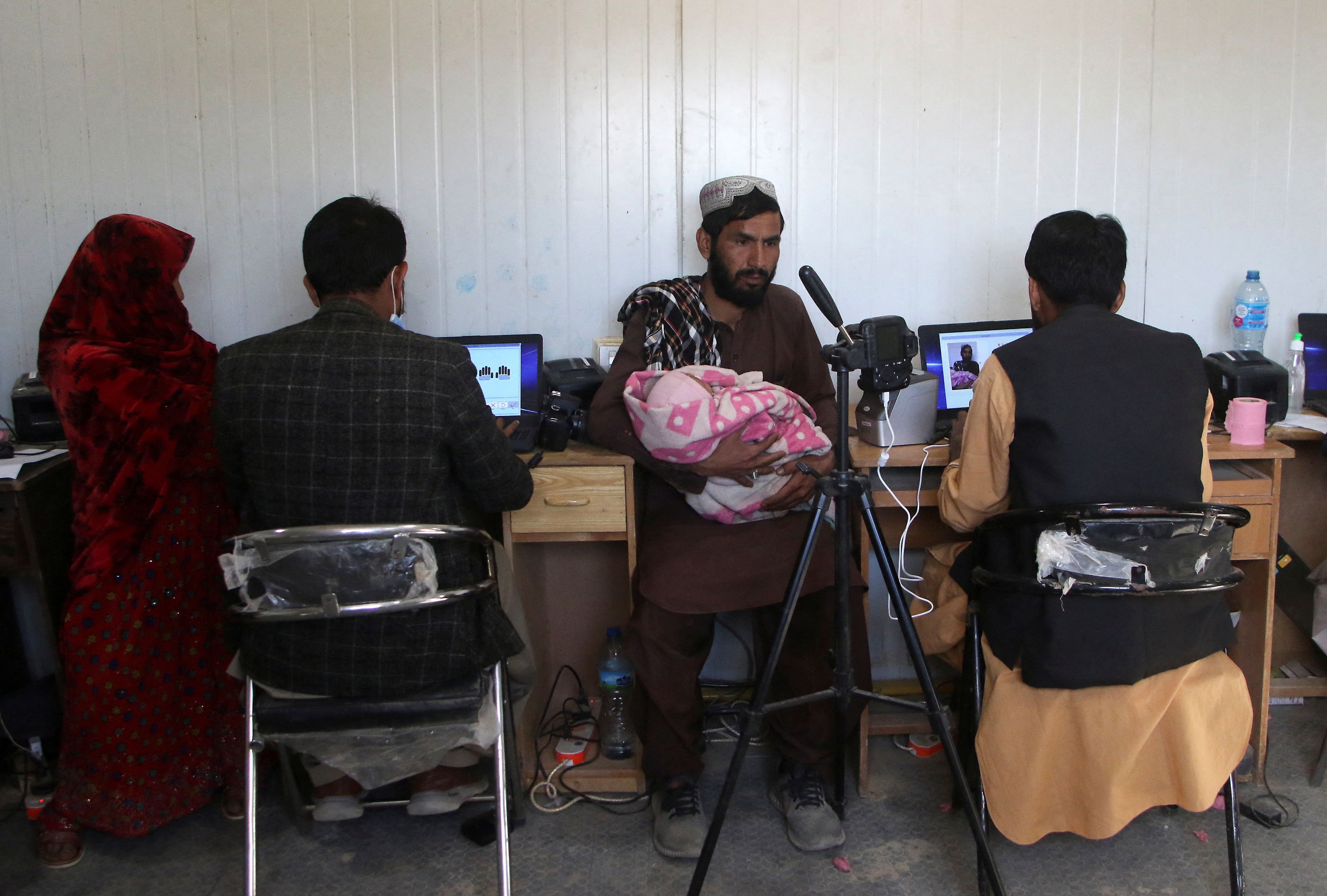 یو کډوال او مېرمن یې چې یو ماشوم یې په غیږ کې دی، د چمن پر پوله افغانستان ته د ننوتلو دمخه د ګوتو نښې ورکوي