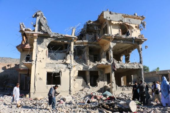 تجمع باشندگان و طالبان در نزدیکی ساختمان تخریبشده پس از حمله هوایی در ولسوالی سمکنی افغانستان، ۲۹ جون.