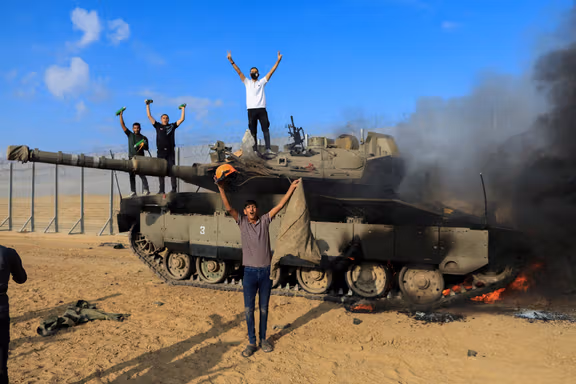 شادمانی فلسطینیها در نزدیک یک تانک اسرائیلی که توسط جنگجویان حماس در ۷ اکتوبر تخریب شد.