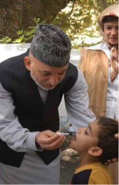 حامد کرزی، رئیس‌جمهور پیشین افغانستان، هنگام تطبیق واکسین پولیو به یک کودک در سال ۱۳۸۵.