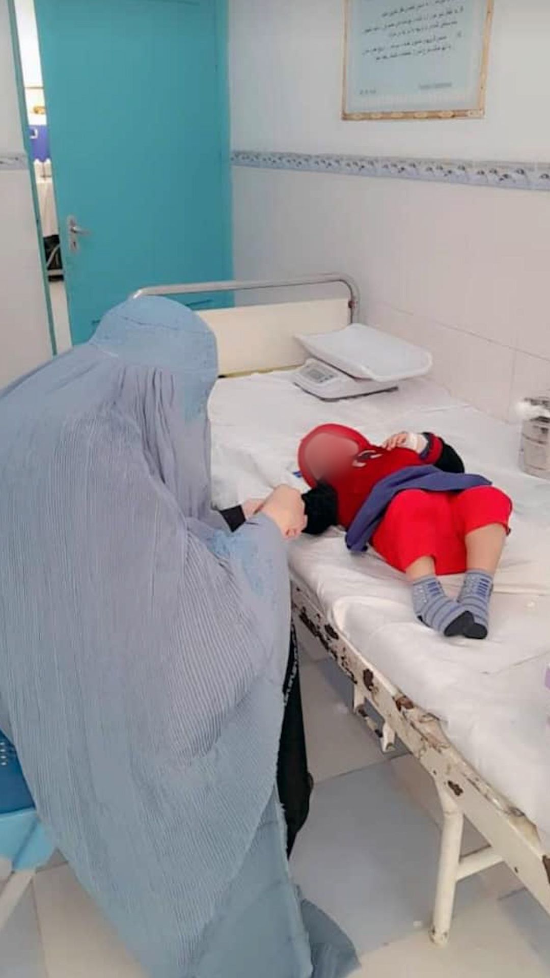 پرستار چادری‌پوش در هرات در حال تزریق واکسین به یک کودک