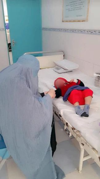 پرستار چادریپوش در هرات در حال تزریق واکسین به یک کودک