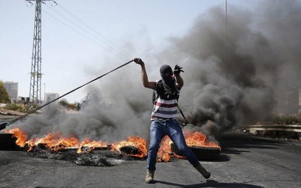 یکی از تظاهرکنندگان فلسطینی در جریان انتفاضه دوم (۲۰۰۰–۲۰۰۵) در برابر موانع آتشین در کرانه باختری.